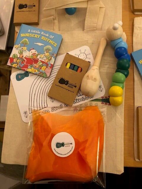 little folk Mini Tote Bag 2 Tote bag contents: 1 small colourful floaty scarf 1 wooden maraca 1 colourful wooden jointed wiggly worm 1 colouring-in card 1 mini-box of crayons 1 little book of nursery rhymes